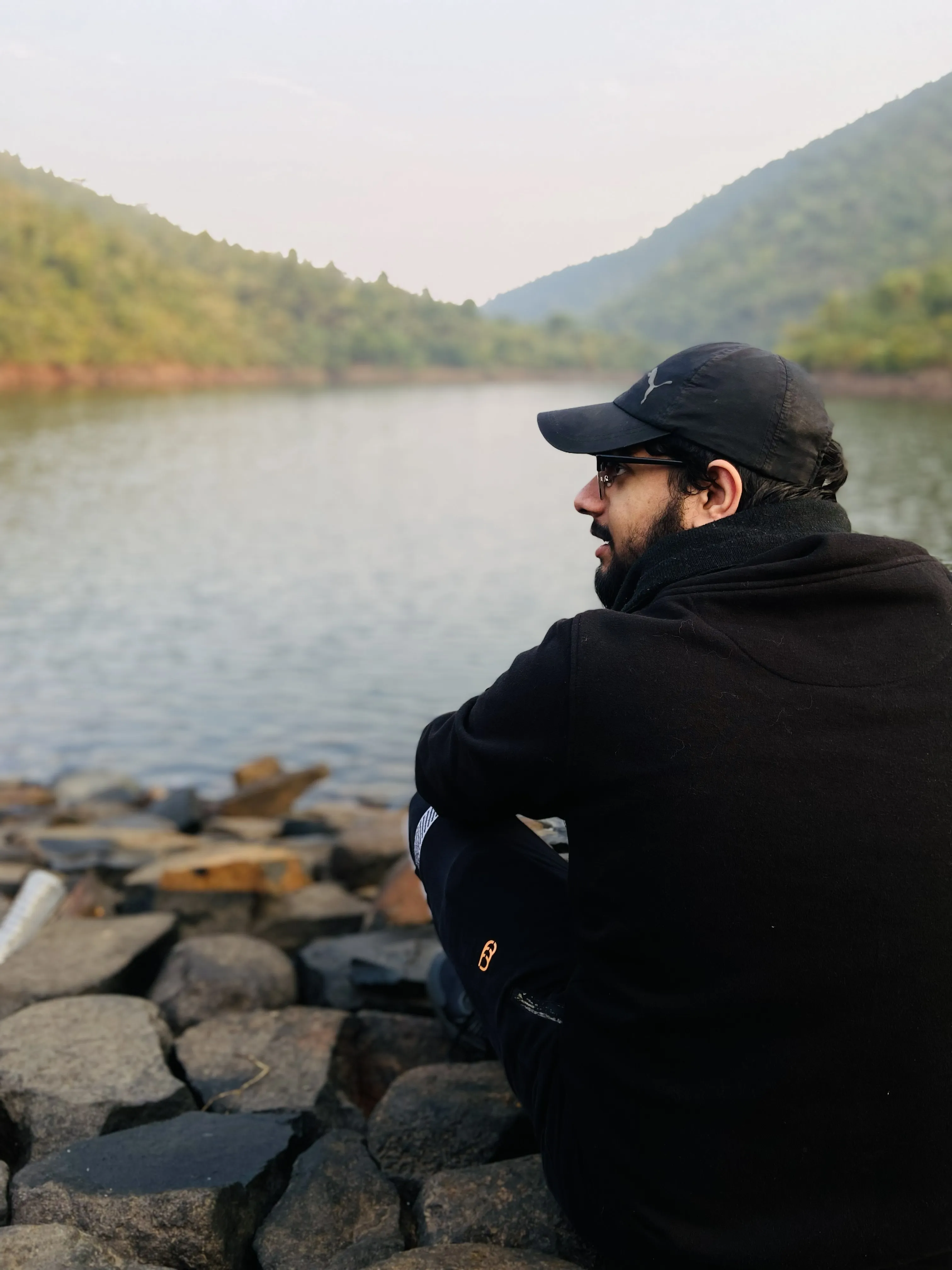 Sitting by a hill-lined reservoir at dawn
